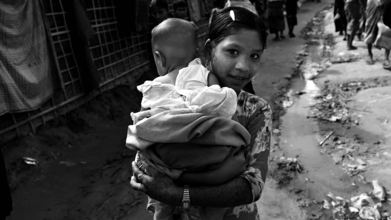 A Rohingya child carries another child