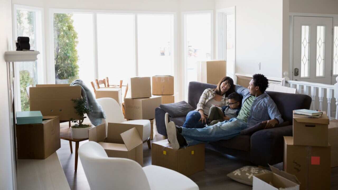 Moving boxes surrounding family relaxing on sofa
