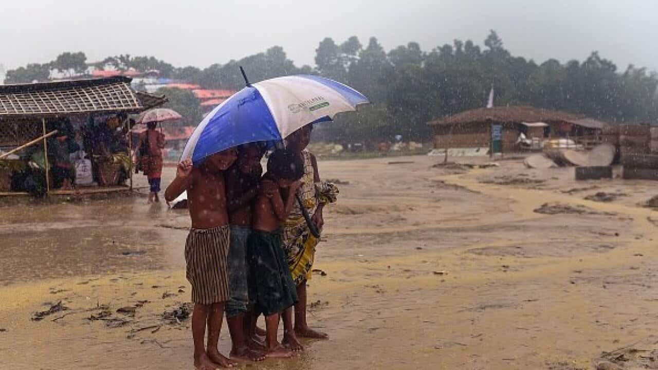 Rohingya refugee children shelter under an umbrella during a rain storm at Balukhali refugee camp in Bangladesh.