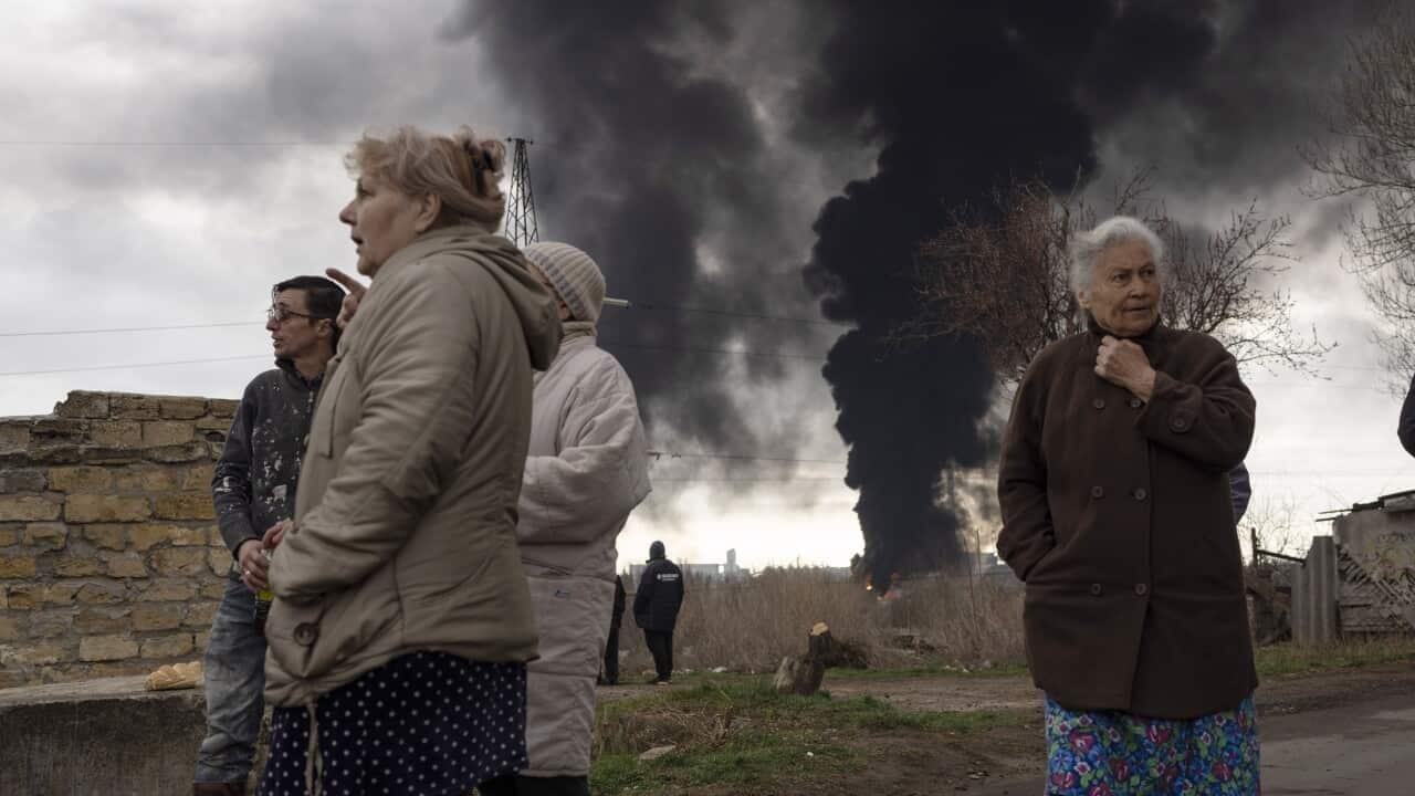 People stay in a yard as smoke rises in the air in the background after shelling in Odesa, Ukraine. Source: AAP / Petros Giannakouris/AP