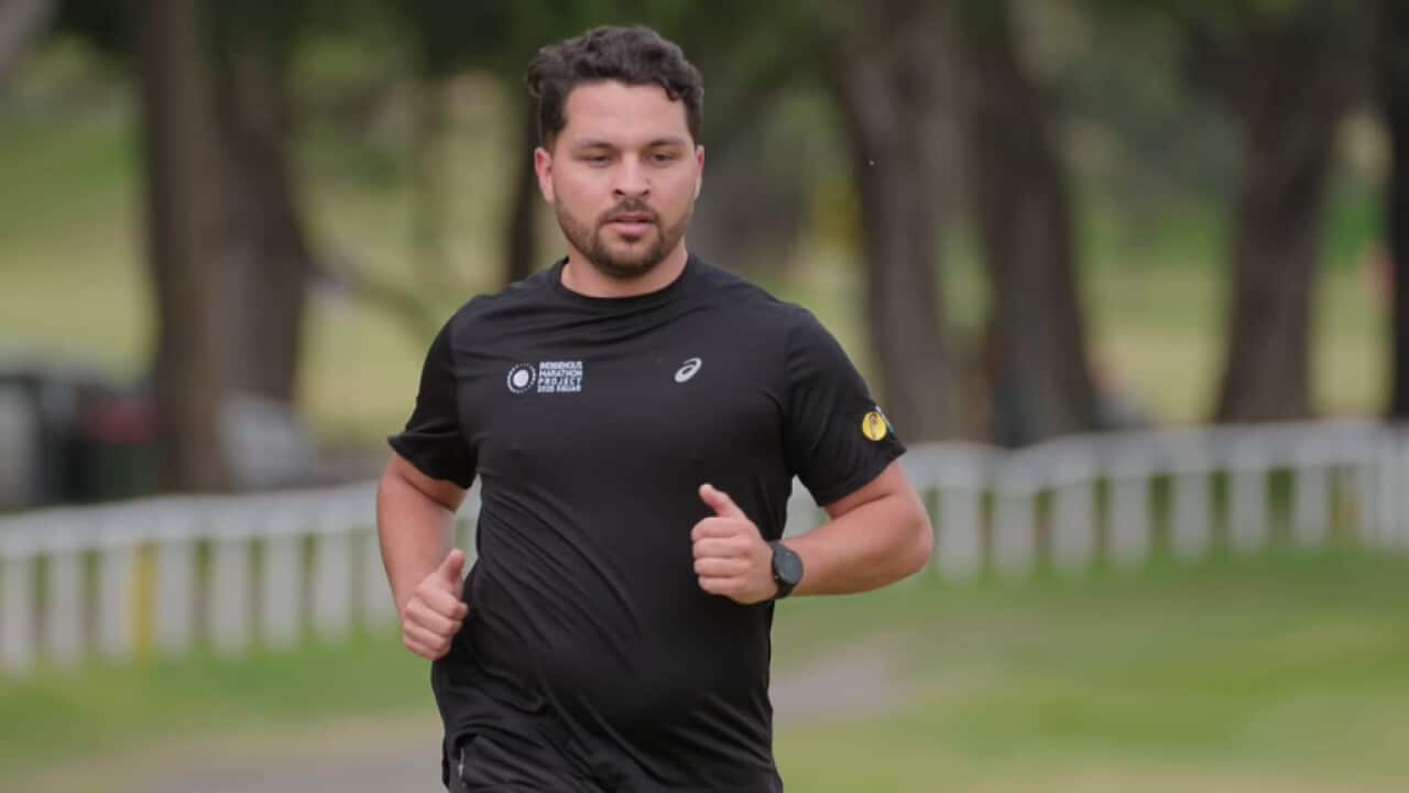 A young Kunjen and Yorta Yorta man runs at a park in Sydney. He wears a black t-shirt with an Indigenous Marathon Project logo.
