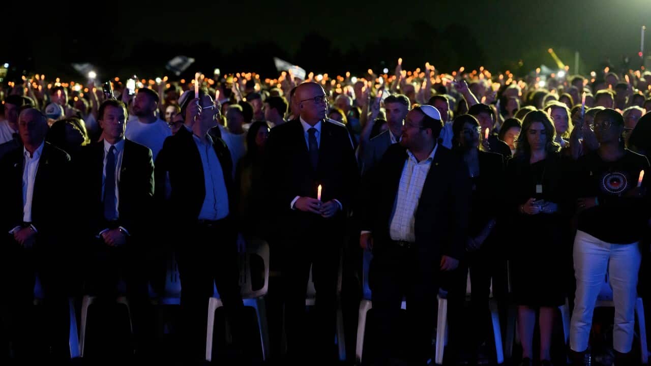 A crowd holds up candles during a vigil.