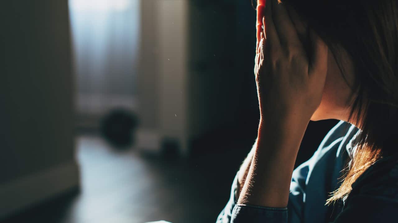 Silhouette of sad and depressed woman sitting on the floor at home