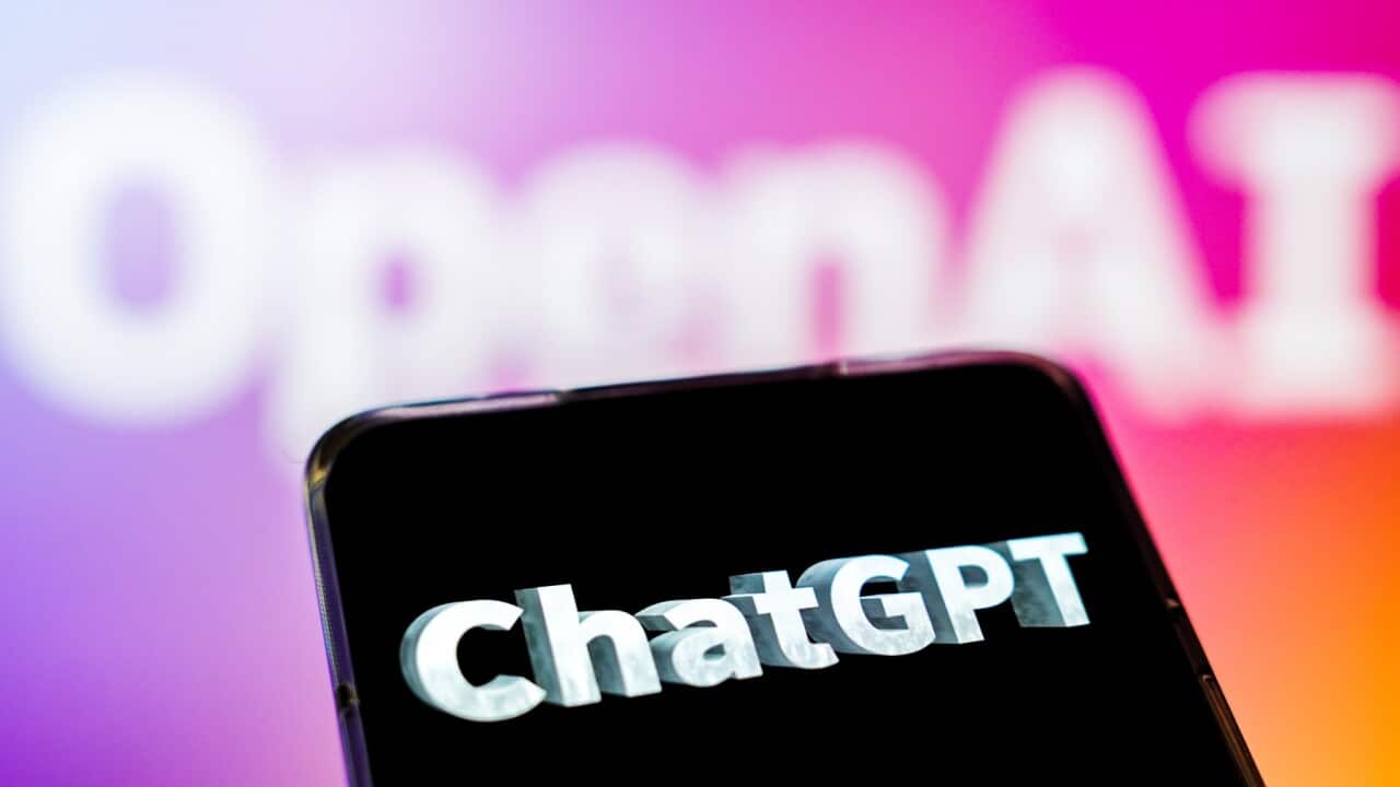 A ChatGPT logo is displayed on the screen of a smartphone with the OpenAI logo in the background.