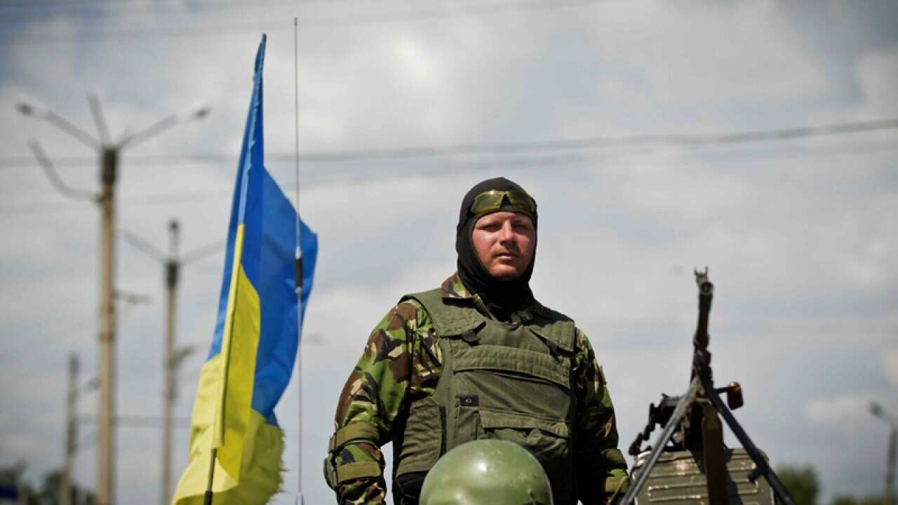 A Ukrainian soldier stands in an armoured vehicle