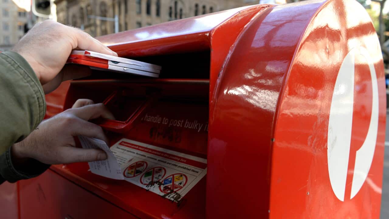 A man posting mail at an Australia Post postbox in Sydney