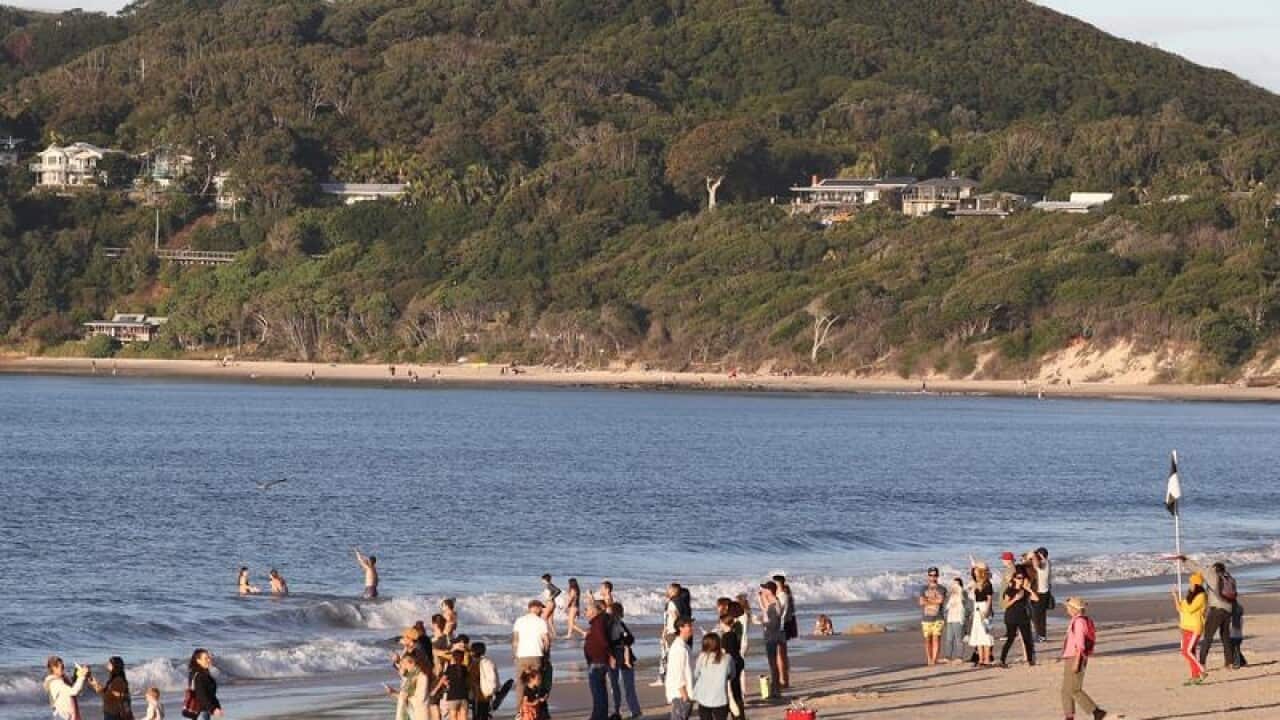 Beachgoers are seen on the sand at Byron Bay