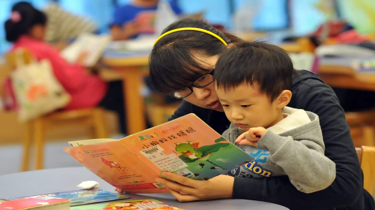 A mother and child read a book together in a public library