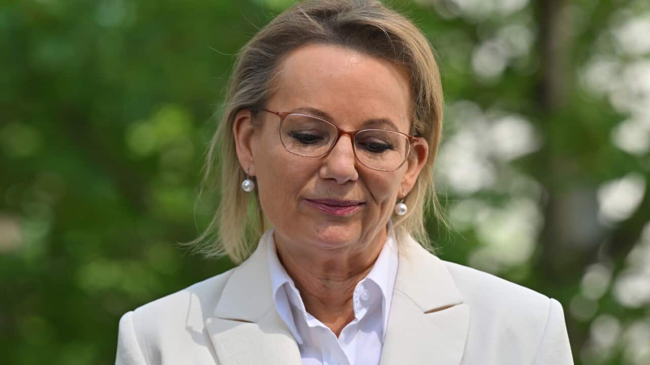 A middle-aged white woman with glasses looking downcast