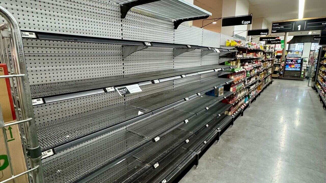 Bare shelves along a supermarket aisle.