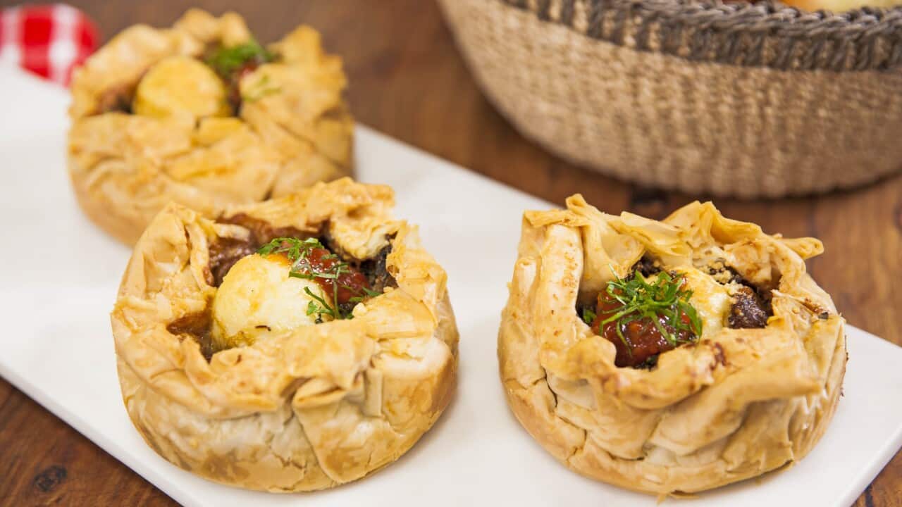 Three round pies sit on a plate, the filling can be seen through a gap in the top of the golden pastry on each.