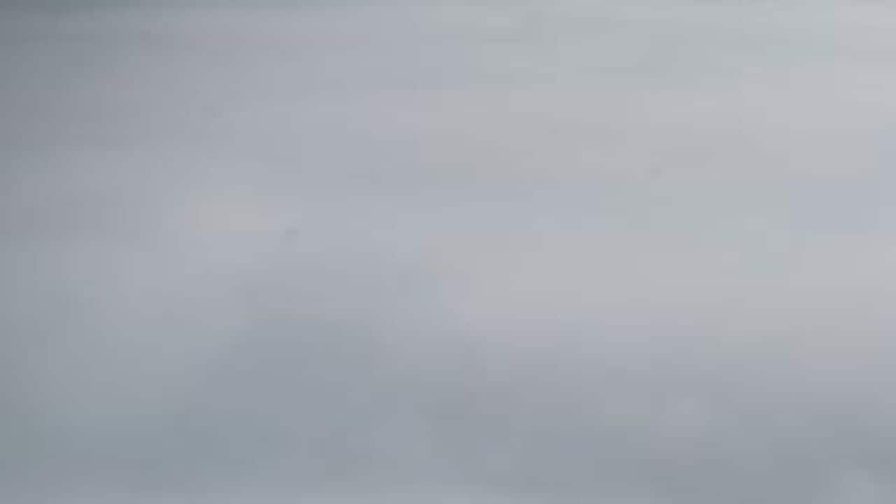 The flag pole of Parliament House in heavy morning fog in Canberra