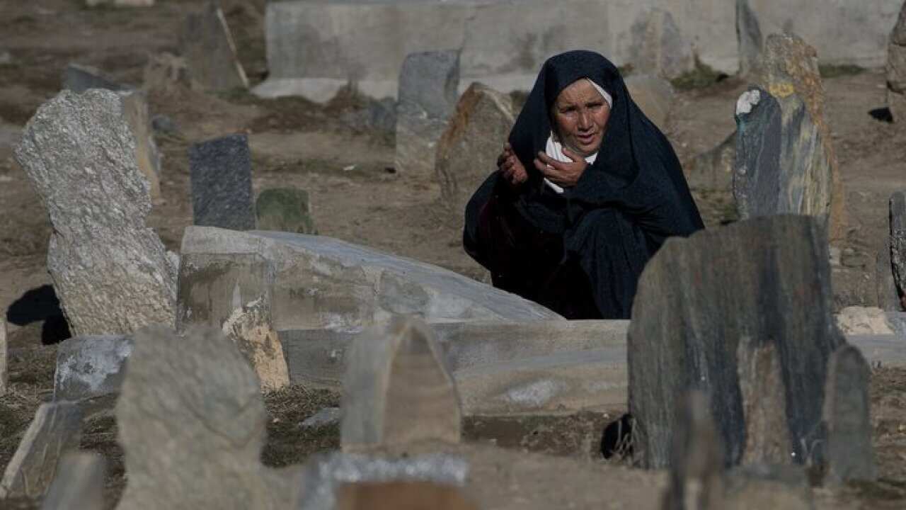 An Afghan resident prays at the grave