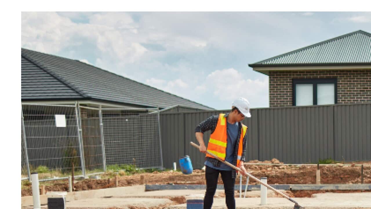 Male worker working at construction site. Young foreman is spreading dry cement