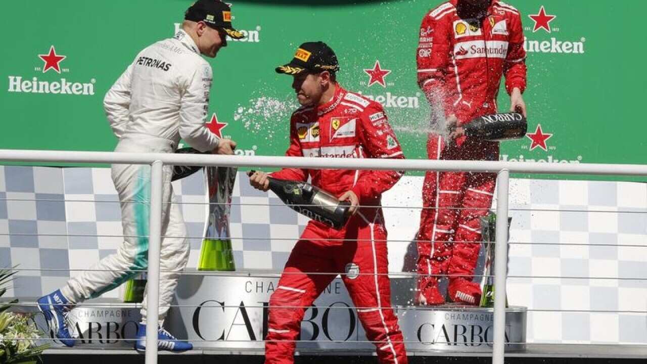 Sebastian Vettel (C) celebrates his victory on podium.