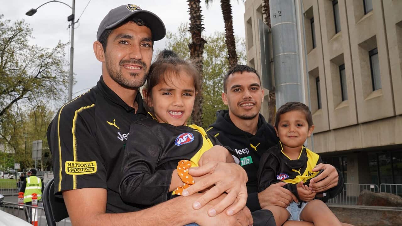 Marlion Pickett of the Tigers holds his daughter Shaniquae during the Grand Finals Parade.