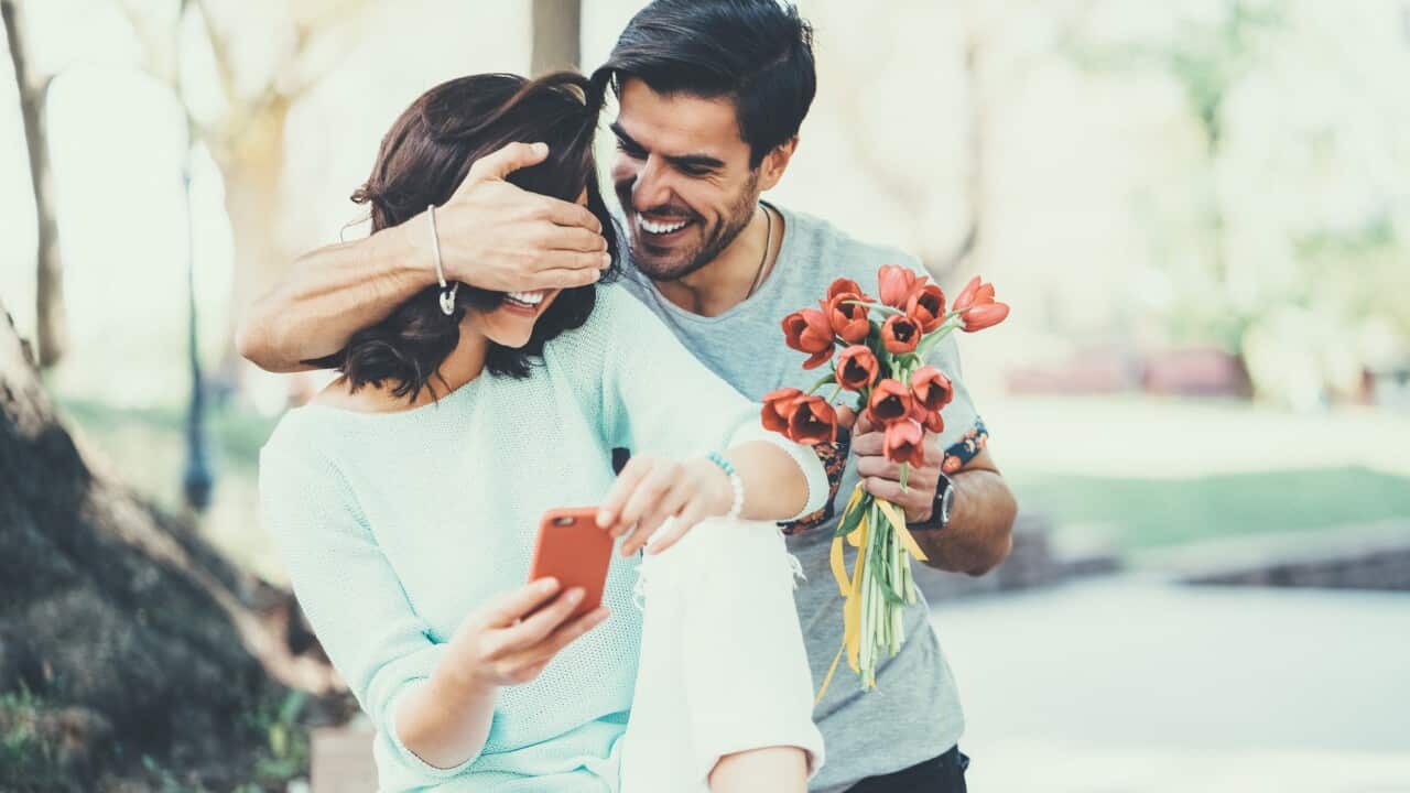 Young man surprising his girlfriend with bouquet of tulips