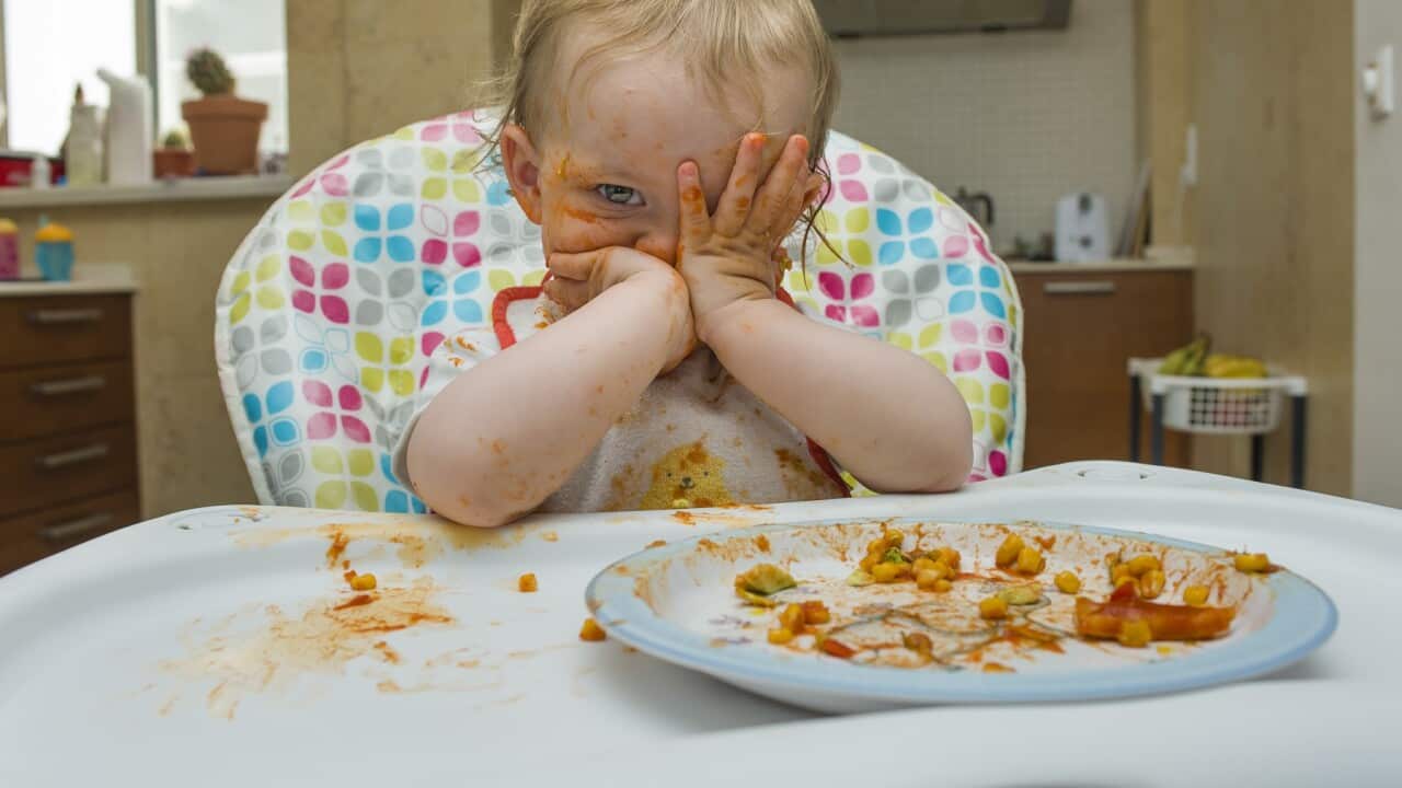 Baby girl eats on a high chair