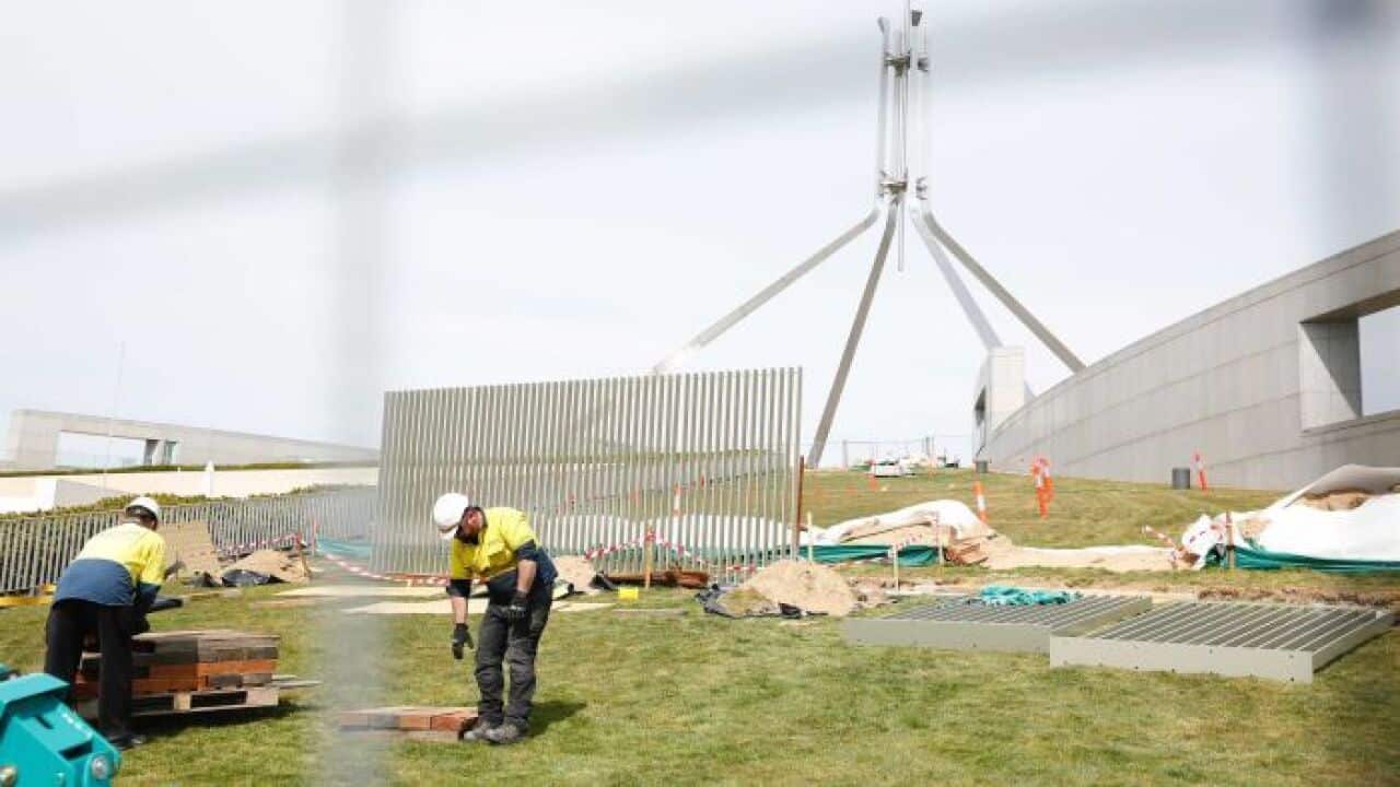 Workers install the new security fence at Parliament House.