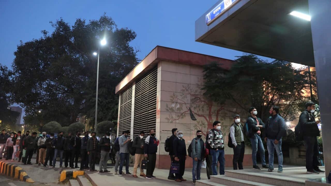 People wait outside a Delhi metro station as public transport restrictions were imposed due to a rise in COVID-19 cases in India's national capital.