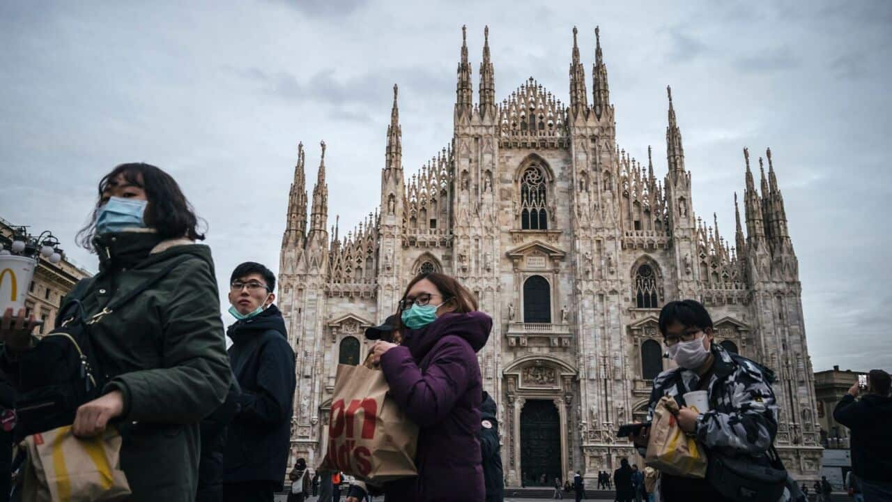 Asian tourists wear protective masks in front of Duomo Cathedral amid Coronavirus fears.