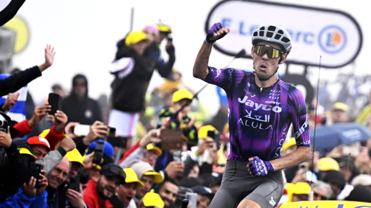 A cyclist celebrating as he rides through a crowd of supporters