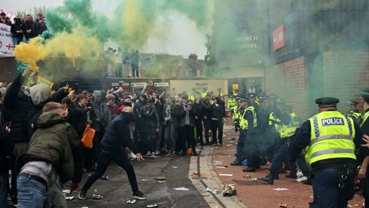 Police try to move people away from the Old Trafford stadium after a supporter's protest against Manchester United's owners