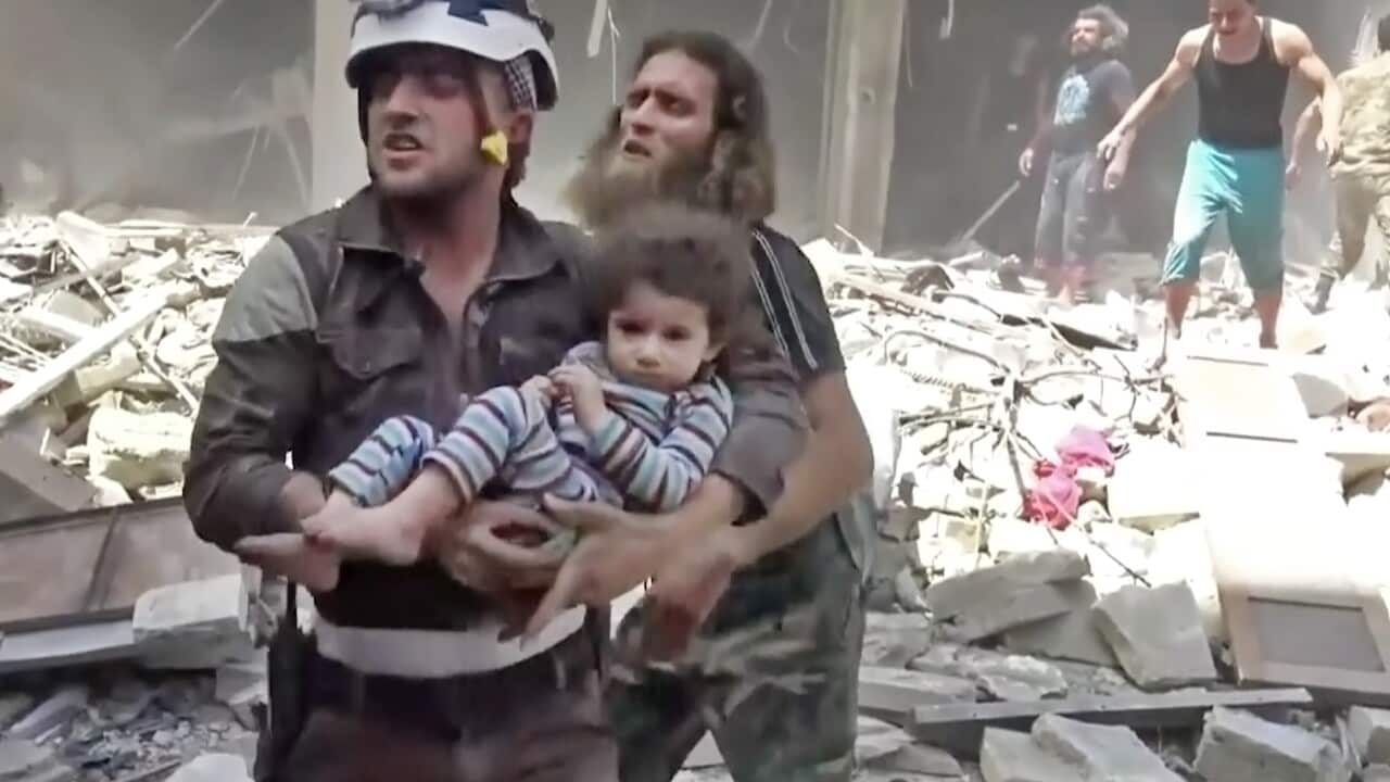 In this image a Civil Defense worker carries a child after airstrikes hit Aleppo, Syria, Thursday, April 28, 2016. 