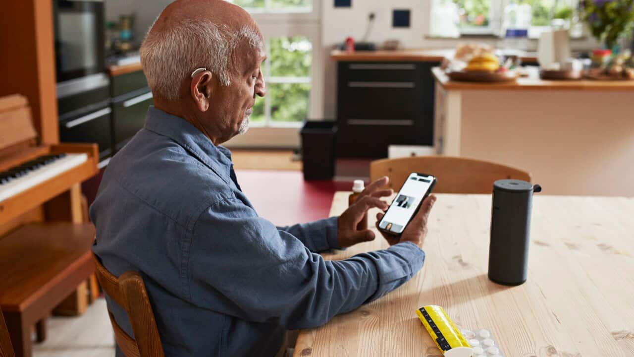 Senior man using smart phone at table