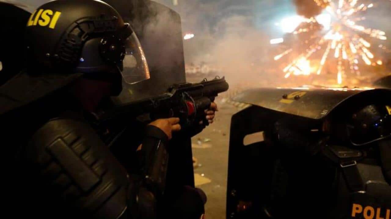 Riot police officer aims tear gas to protesters during a riot near the Election Supervisory Agency (Bawaslu) headquarters in Jakarta, Indonesia, May 22, 2019.