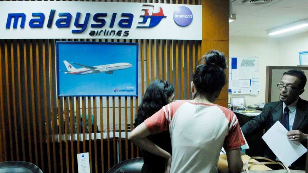A Malaysia Airlines branch office staff member at Jakarta International airport helps relatives with information on July 18, 2014 following the loss of MH17. (AFP)