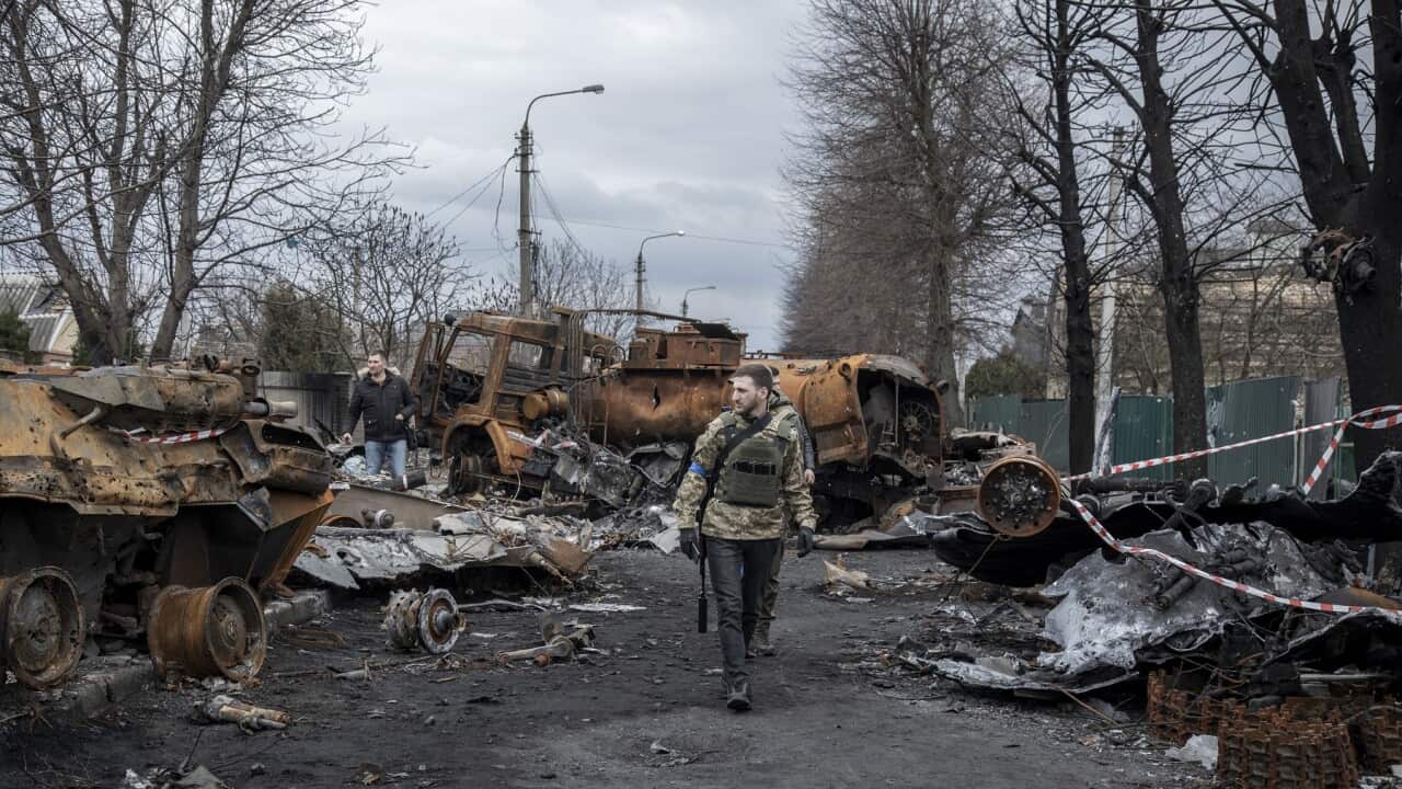 Ukrainian servicemen walk amid the destruction on a street in the town of Bucha