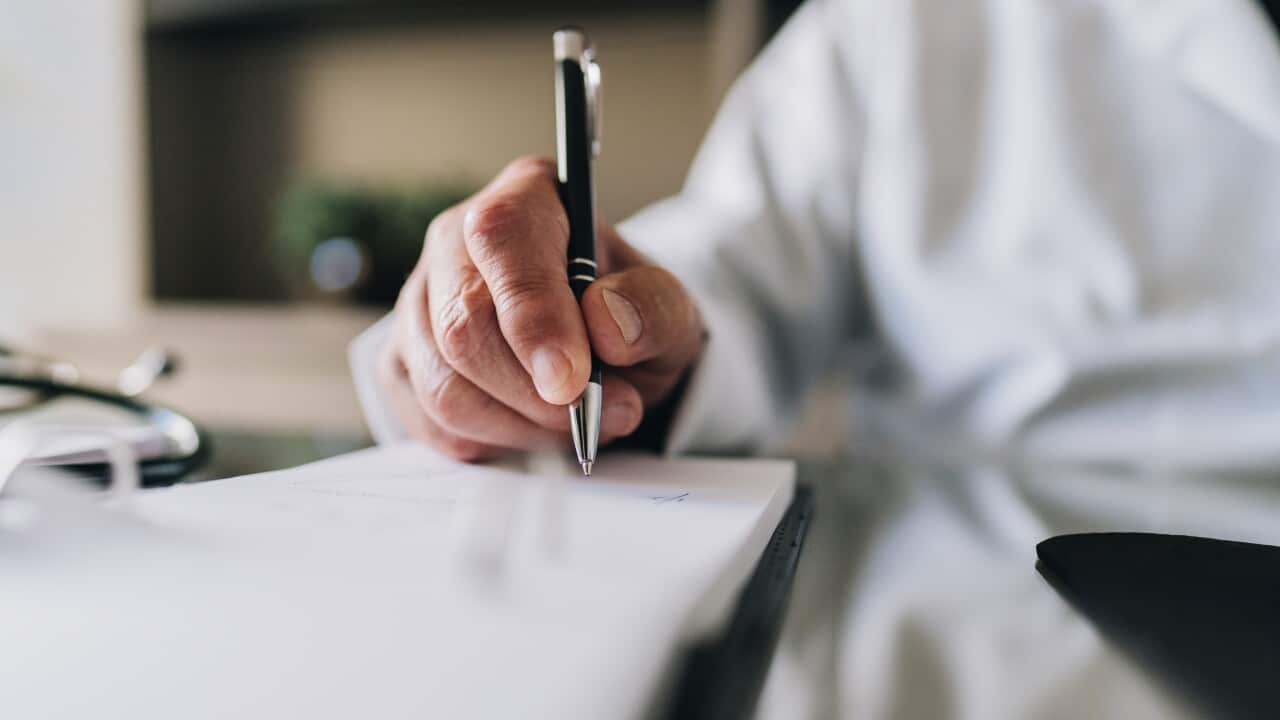 Close-up of a doctor's hand as he writes on a notepad.