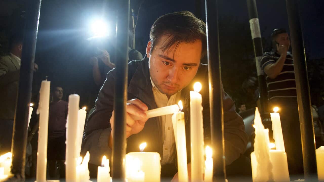 A supporter of the late Chilean President Sebastian Pinera lights candles in the courtyard of the National Renewal political party headquarters, in Santiago, Chile (AAP).