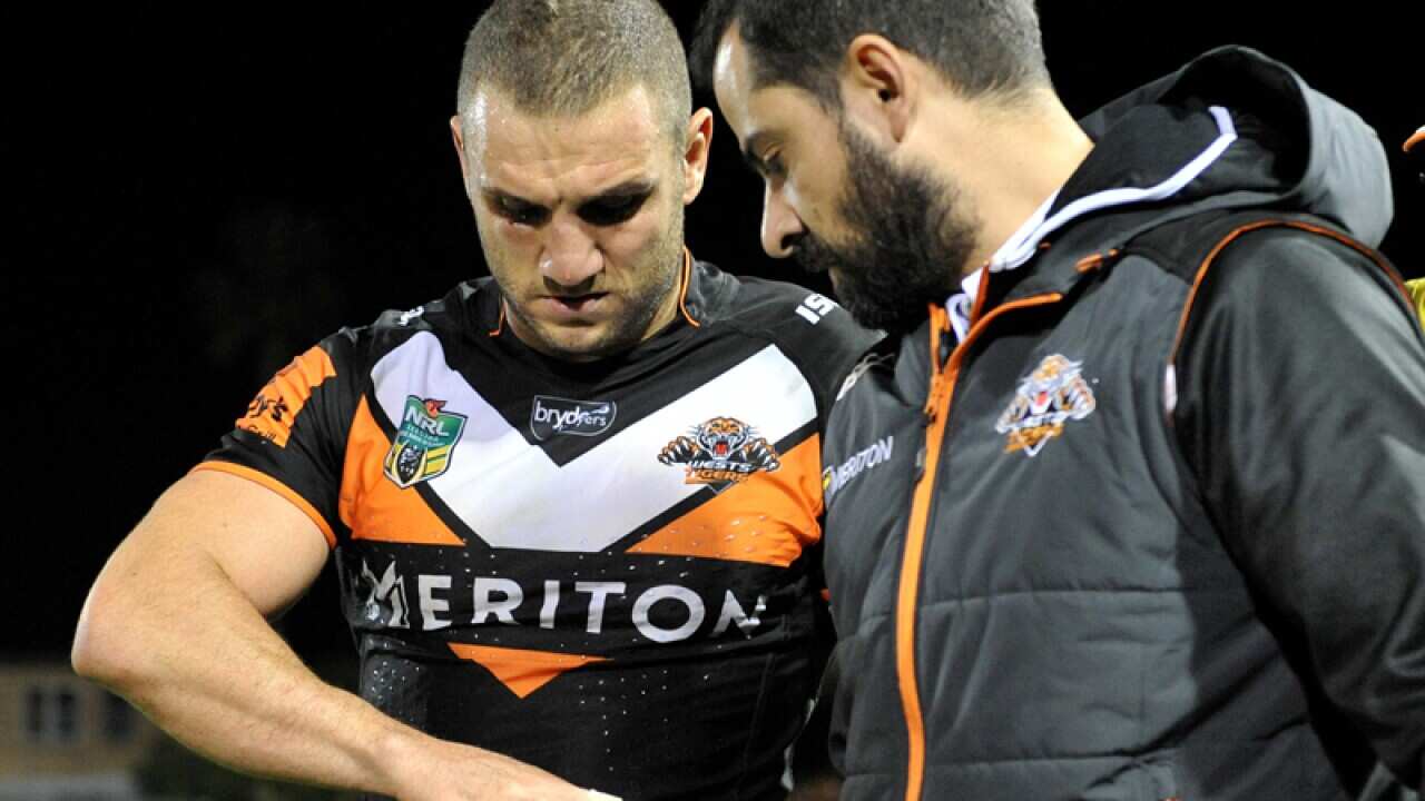 Robbie Farah of the Tigers is assisted off the field with an injury