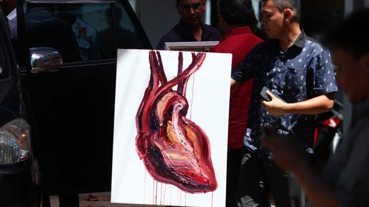A man carry a Myuran's painting "satu hati, satu rasa di dalam cinta"at Wijaya Pura port in Cilacap, Central Java, Indonesia, Tuesday, April 28, 2015. (AAP Image/Roni Bintang) 