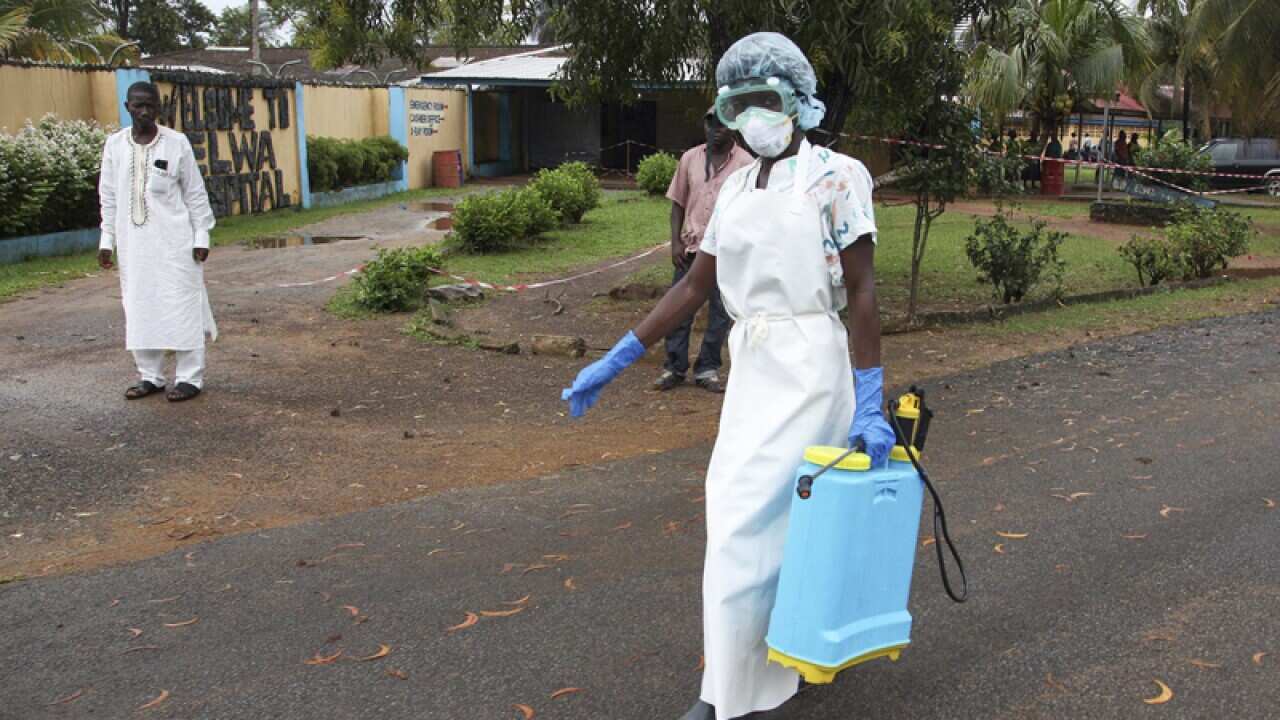 A nurse from Liberia walks to spray preventives