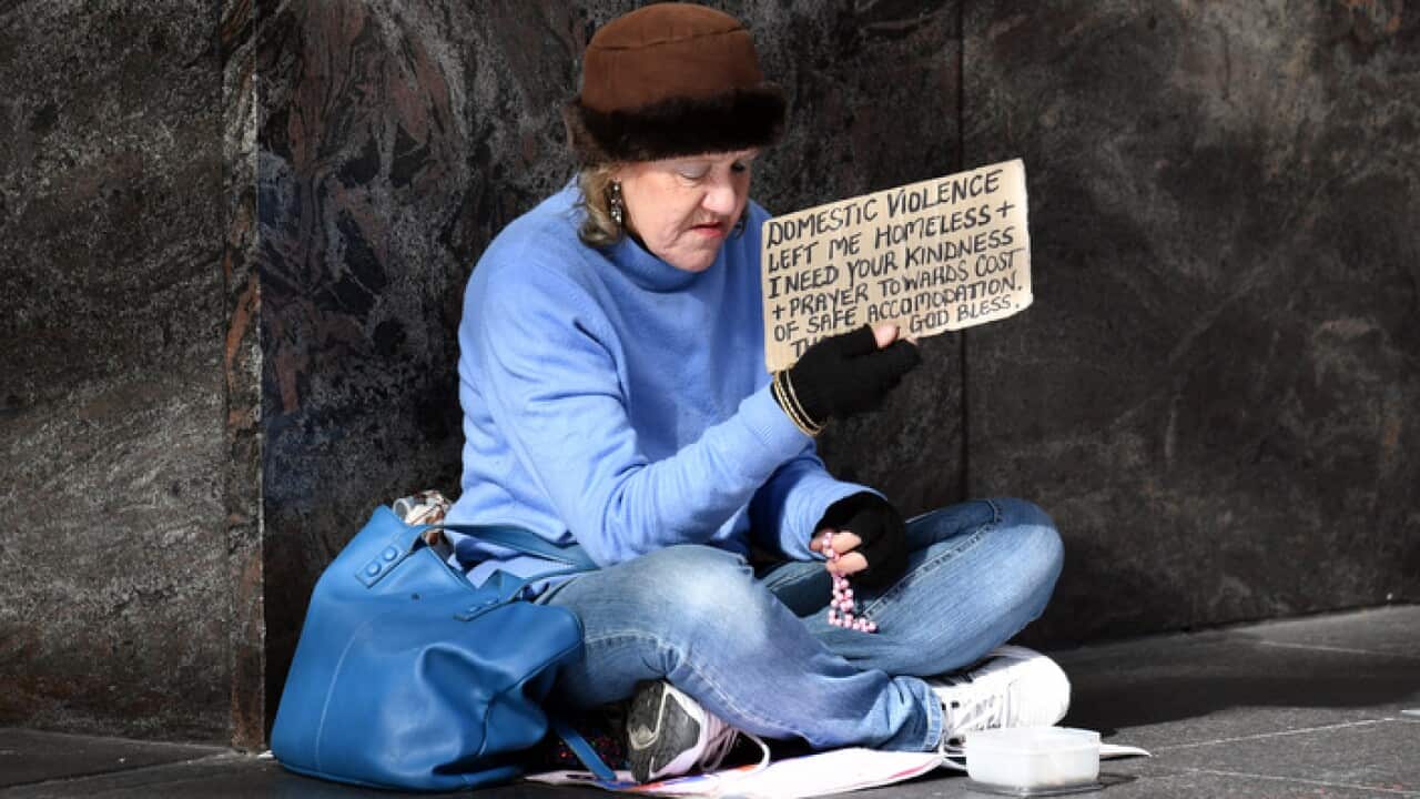 A homeless woman holding a sign saying she is a victim of domestic violence asks for money on the street in Sydney, Monday, July 9, 2018. (AAP Image/Mick Tsikas) NO ARCHIVING