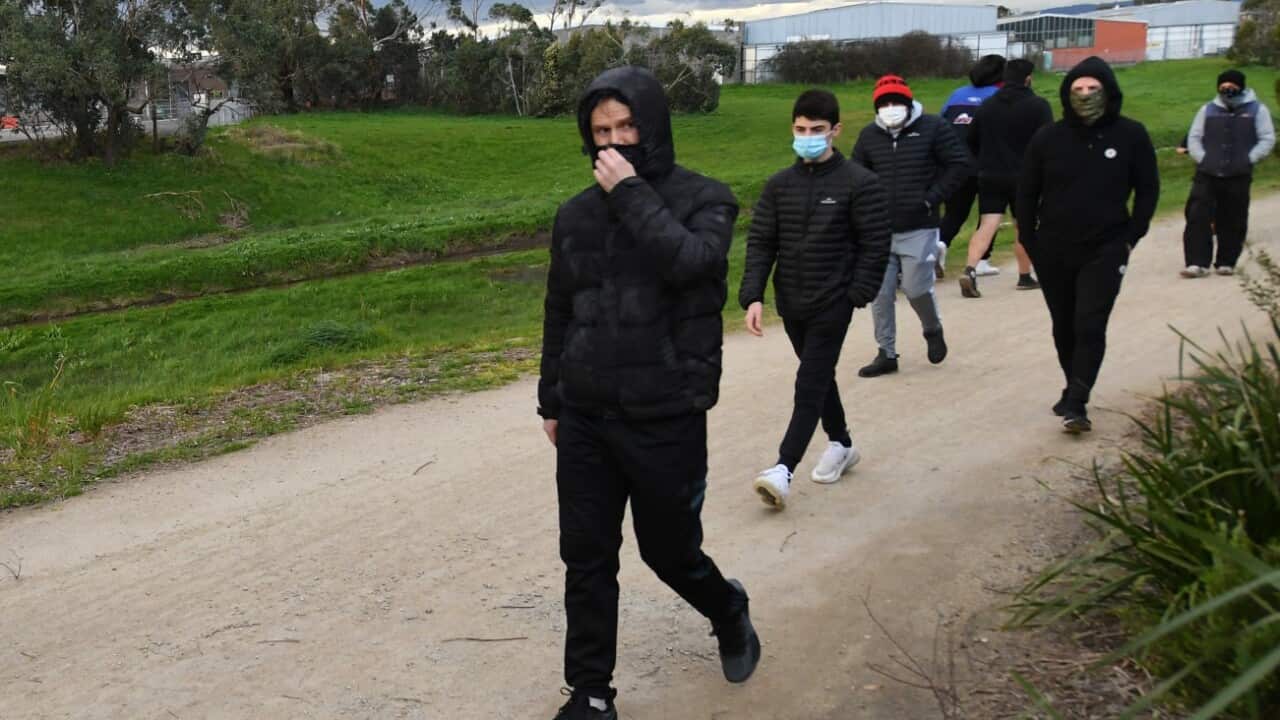 Victorian Police look on as people walk along a track in Dandenong, Melbourne, Thursday, August 27, 2020.
