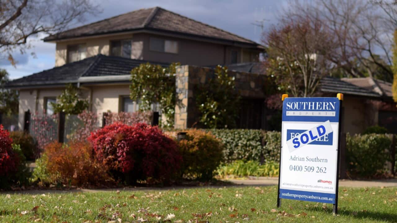 A sale sign is seen in front of a house.