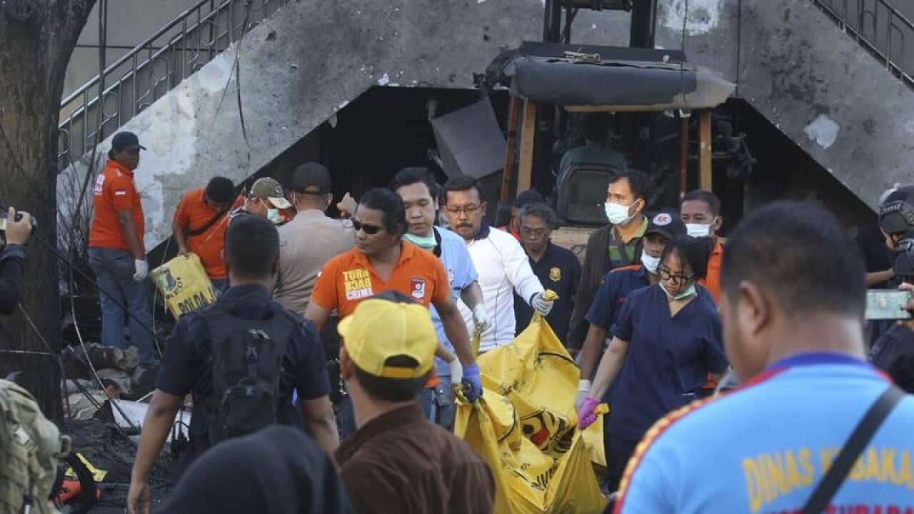 Officers carry a body bag out of one of the bomb sites