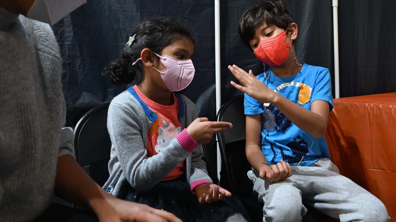 Sanaa, 5, and her brother Arin, 7, play rock-paper-scissor to decide who will go first in getting their Pfizer dose.