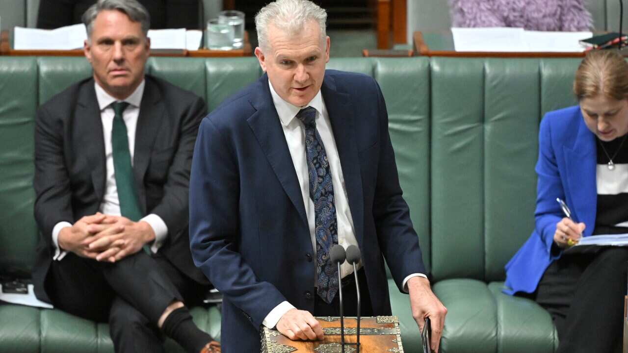 A man in a suit speaks at a lectern.