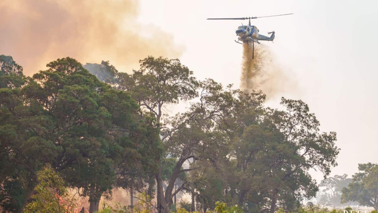 A helicopter flying over fire in bushland