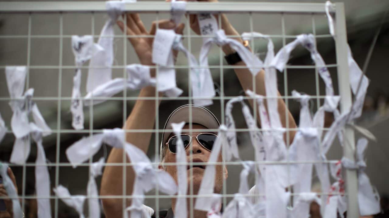 An elderly man ties ribbons with messages of support for young protesters during a rally in Hong Kong.