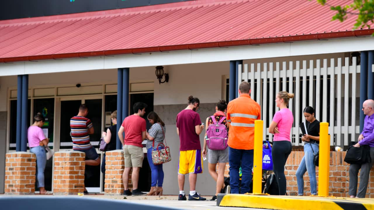 People are seen in a long queue outside a Centrelink office in Brisbane, Tuesday, March 24, 2020