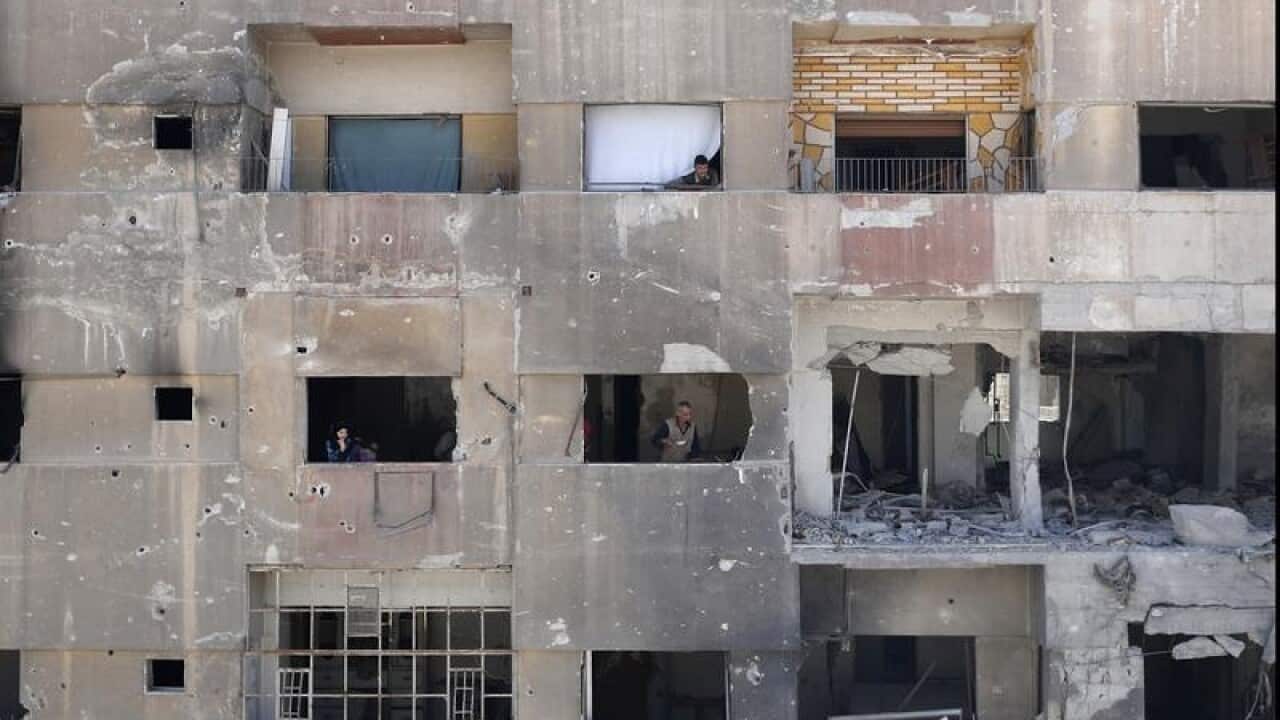 Residents survey the damage in Douma.