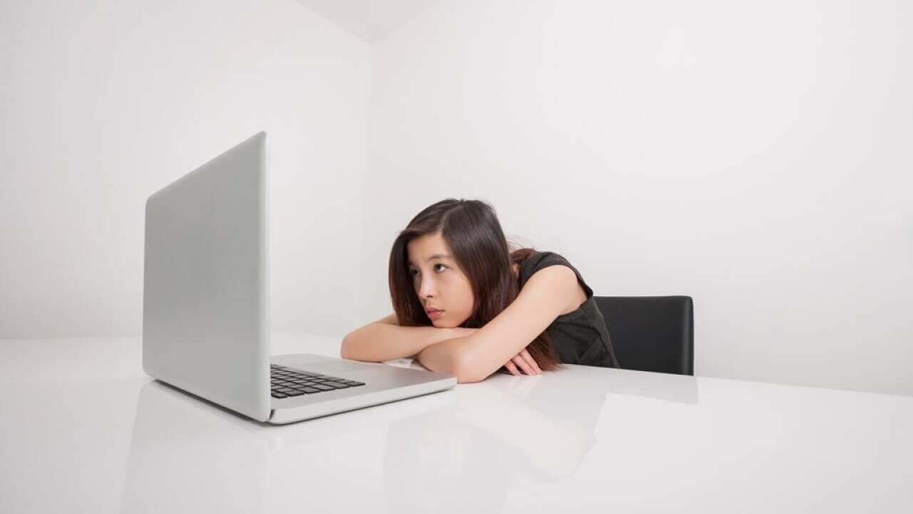 Bored young woman looking at laptop in office