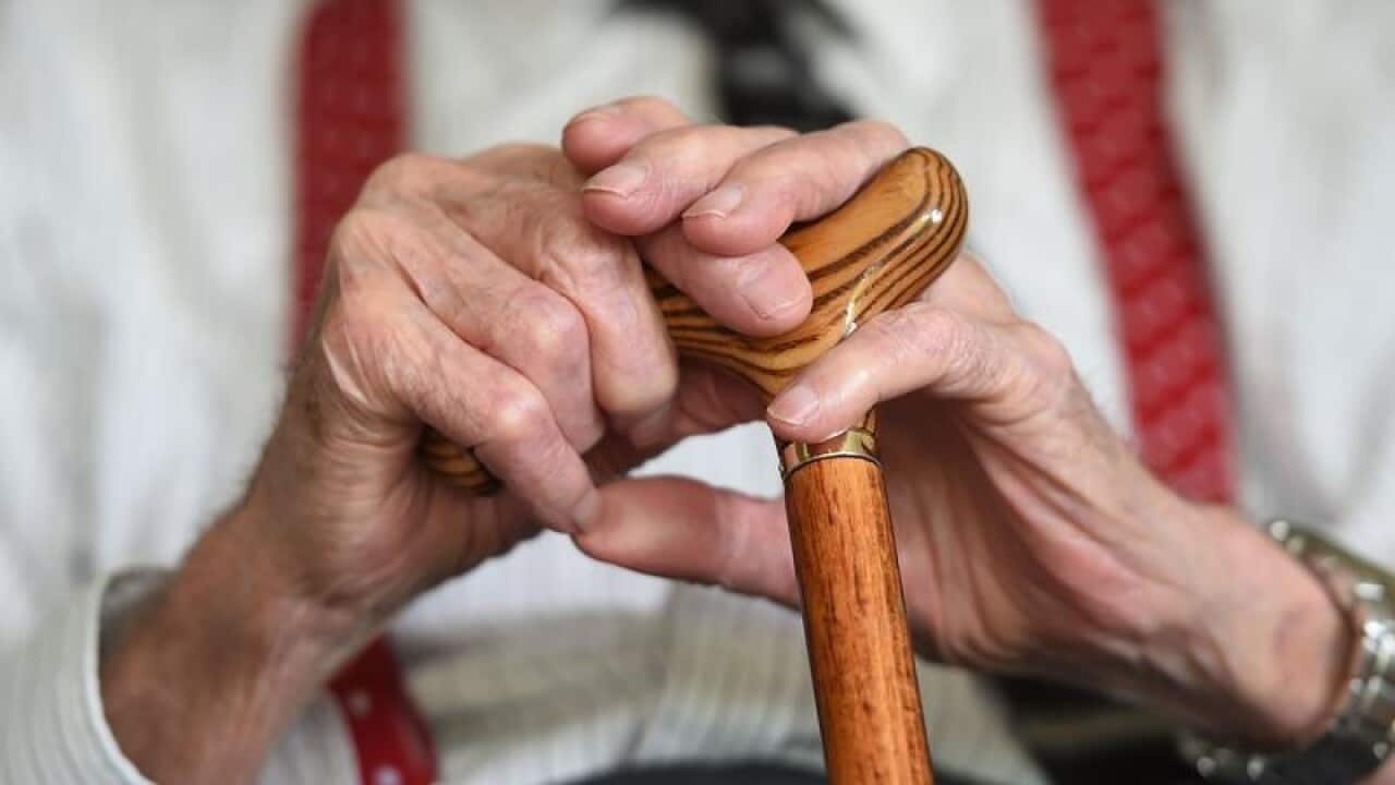 close up of elderly man's hands holding walking stick