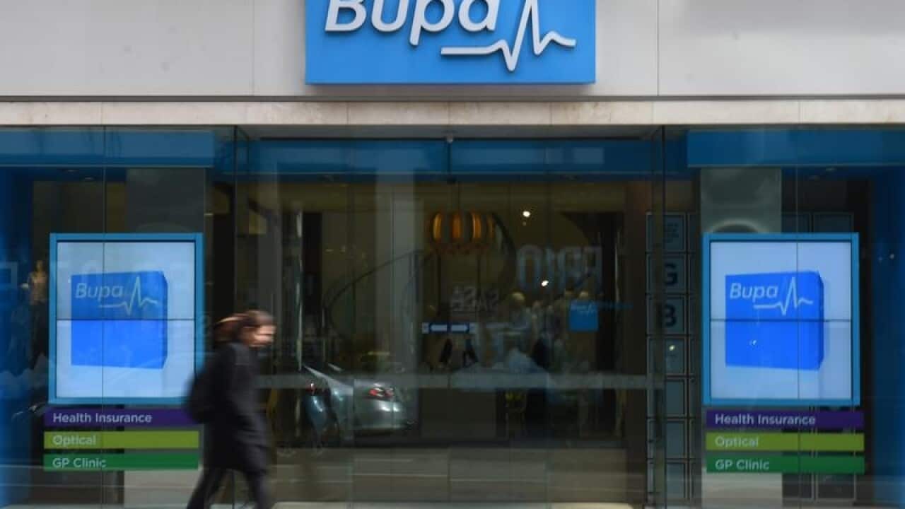 A woman walks past a Bupa Health Insurance branch.